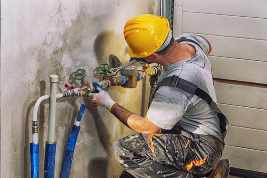 Plumber fixing pipes under a sink